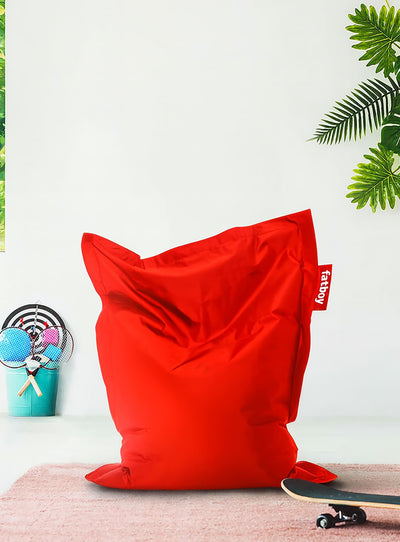 Red bean bag chair with a 'Fatboy' tag on a white background with plants.