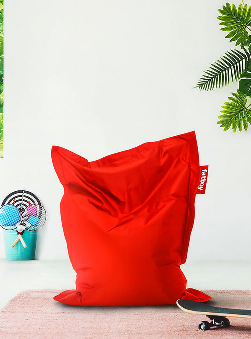 Red bean bag chair with a 'Fatboy' tag on a white background with plants.