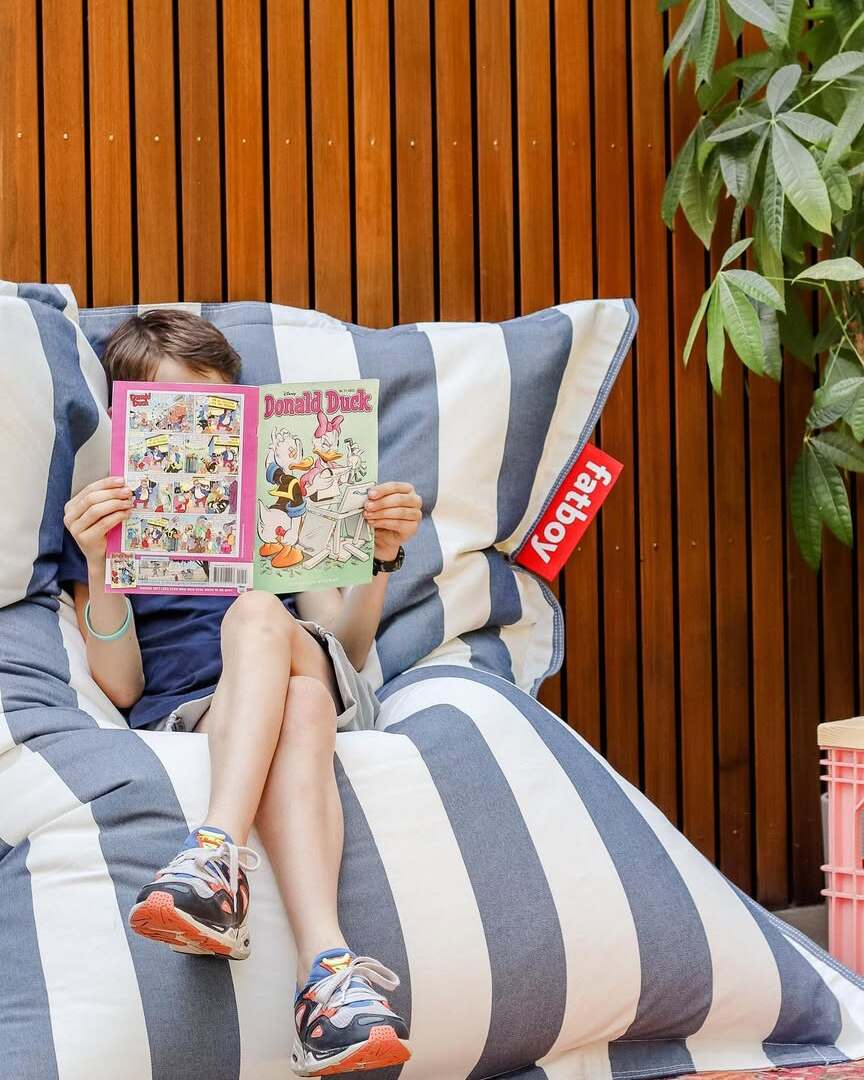 Child studying outdoors on a Fatboy Original Olefin bean bag, enjoying fresh air.