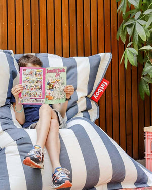 Child studying outdoors on a Fatboy Original Olefin bean bag, enjoying fresh air.