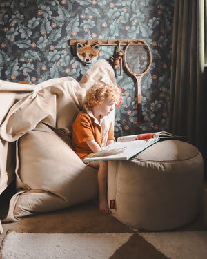 Child lounging on a soft Slim Velvet bean bag in a cozy corner, with books and headphones nearby.